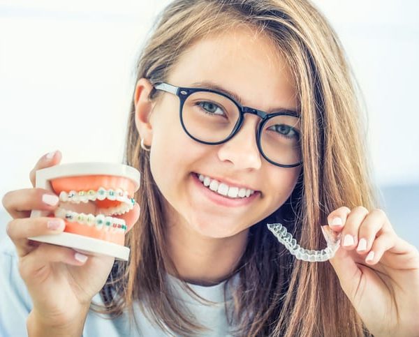 Dental invisible braces or silicone trainer in the hands of a young smiling girl.