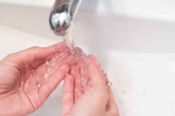 woman's hands washing her invisible aligners for dental correction with water