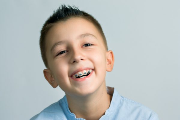 young boy wearing braces happily
